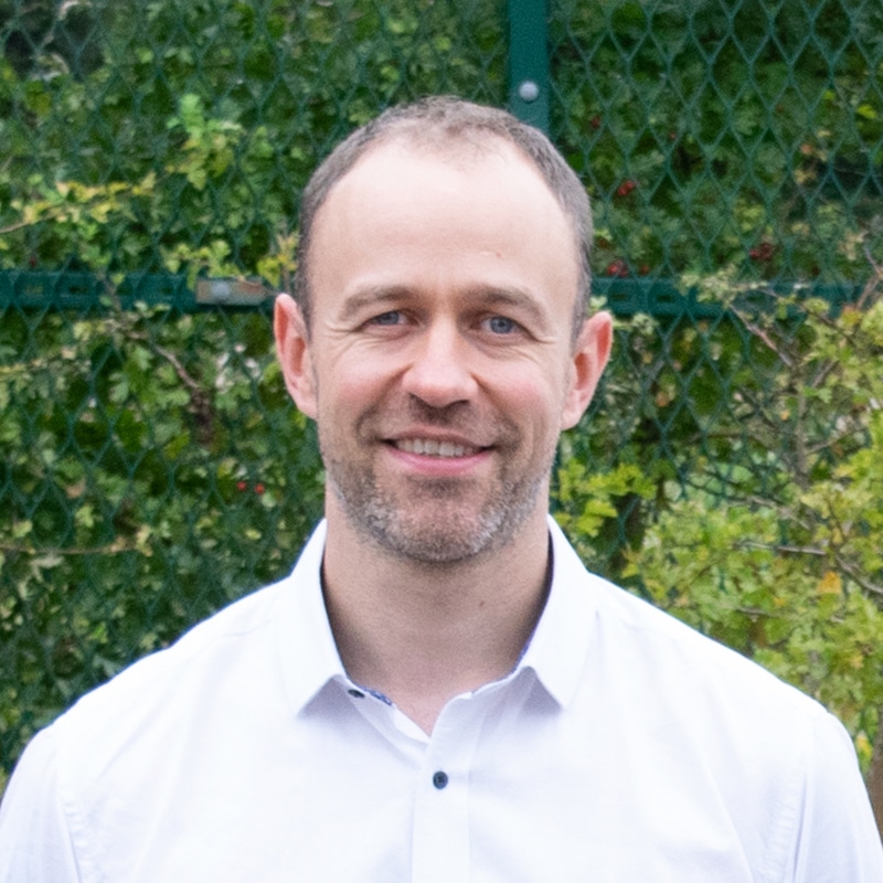 Ben Dixon, consultant at Create Consulting Engineers, wearing white shirt against green foliage background