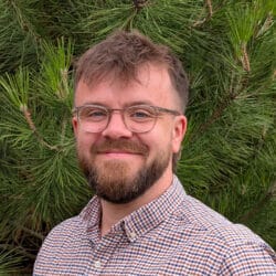 Sam Ward, Acoustic Consultant at Create Consulting Engineers, wearing glasses and checkered shirt