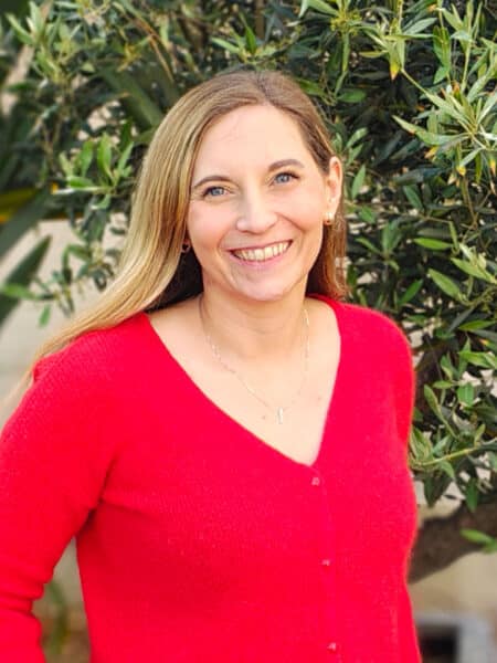Claire Burroughs, Civil and Environmental Engineer and Technical Director at Create Consulting Engineers, outdoors wearing red cardigan.