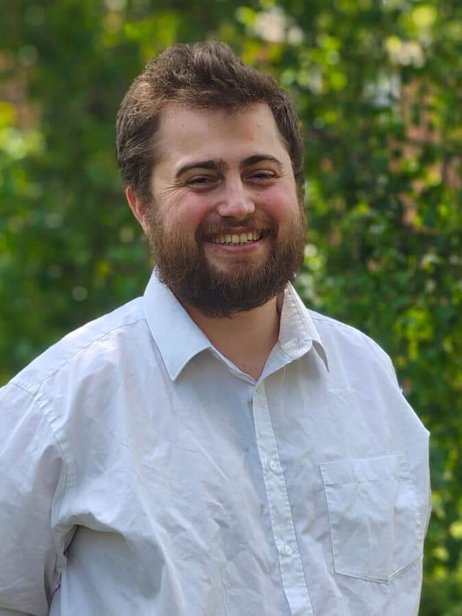 George Baker, Flood Risk Consultant at Create Consulting Engineers, smiling outdoors in professional white shirt.