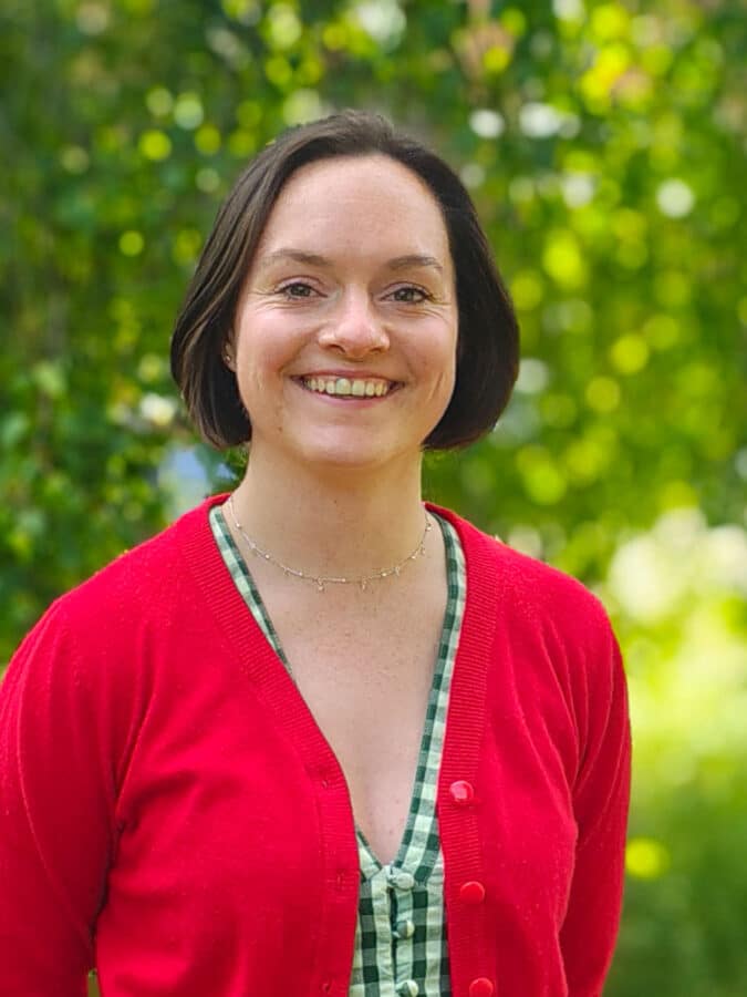 Grace Beard, Flood Risk Consultant at Create Consulting Engineers, smiling outdoors against green foliage background.