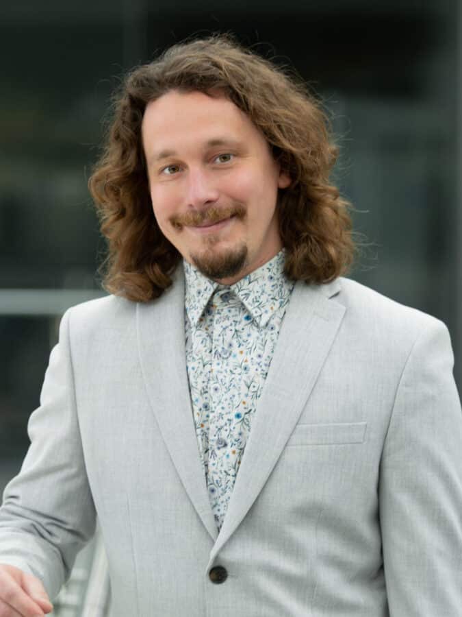 Mat Tuora, Principal Acoustic Consultant at Create Consulting Engineers, wearing a light grey blazer and patterned shirt.