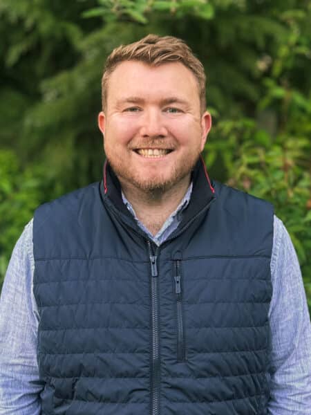 Matthew Wellington, Brand, Marketing and Proposals Manager at Create Consulting Engineers, smiling outdoors wearing navy gilet and light blue shirt.