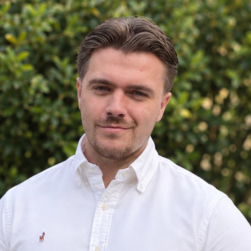 Joshua Weston, professional at Create Consulting Engineers, wearing a white button-up shirt against a blurred green background.