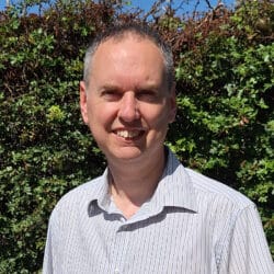 Jon Plastow, Principal Civil Engineer at Create Consulting Engineers, smiling outdoors against green foliage background.
