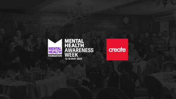 A large group of people pose together in a banquet hall behind logos for Mental Health Awareness Week 2025 and Create.
