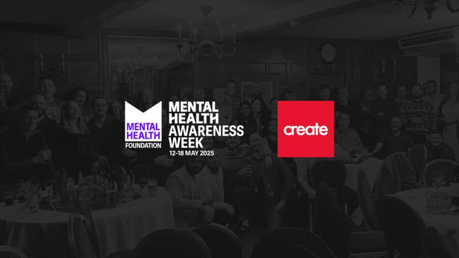 A large group of people pose together in a banquet hall behind logos for Mental Health Awareness Week 2025 and Create.