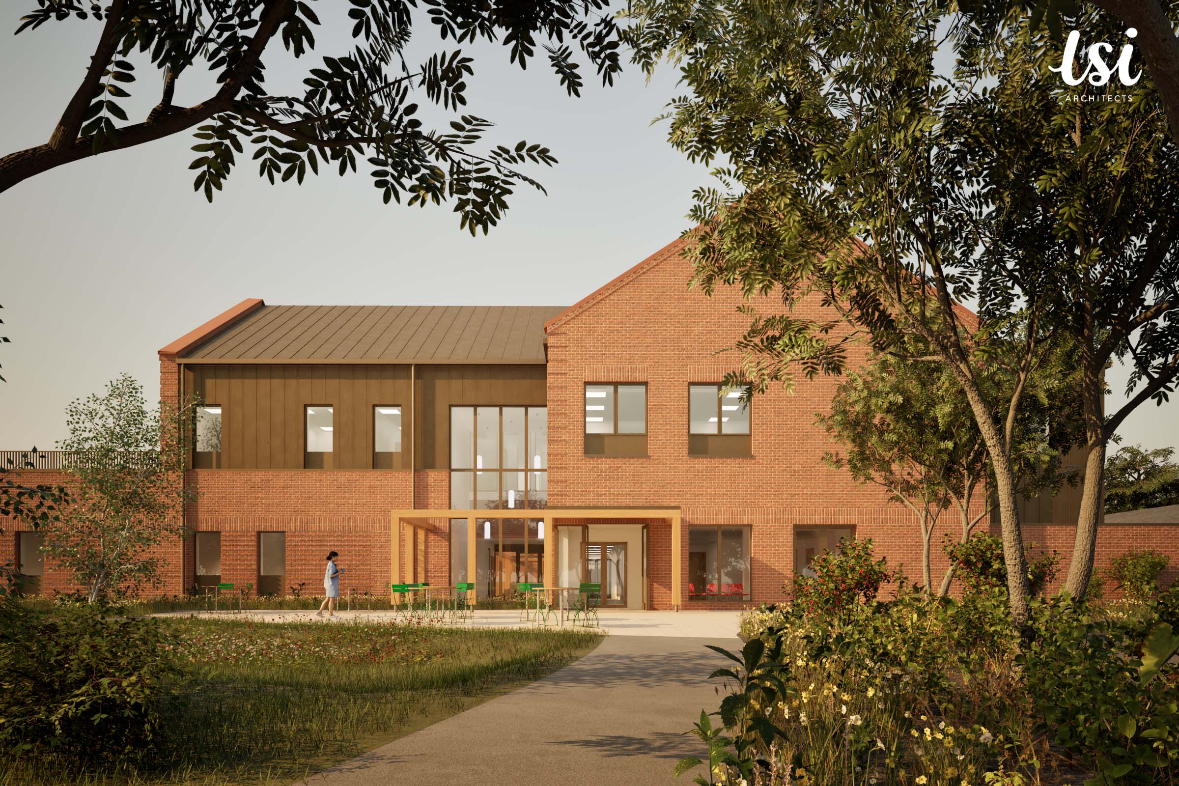 A modern two-story brick building with large windows and a glass entrance, surrounded by greenery and a walking path under a clear sky.