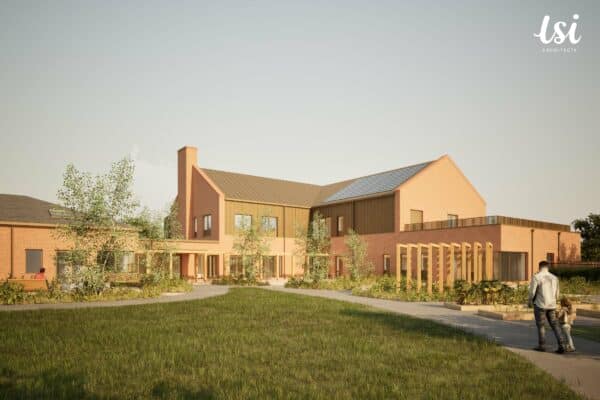 Two people walk on a curved path toward a modern brick building with large windows, a chimney, and landscaped gardens under a clear sky.