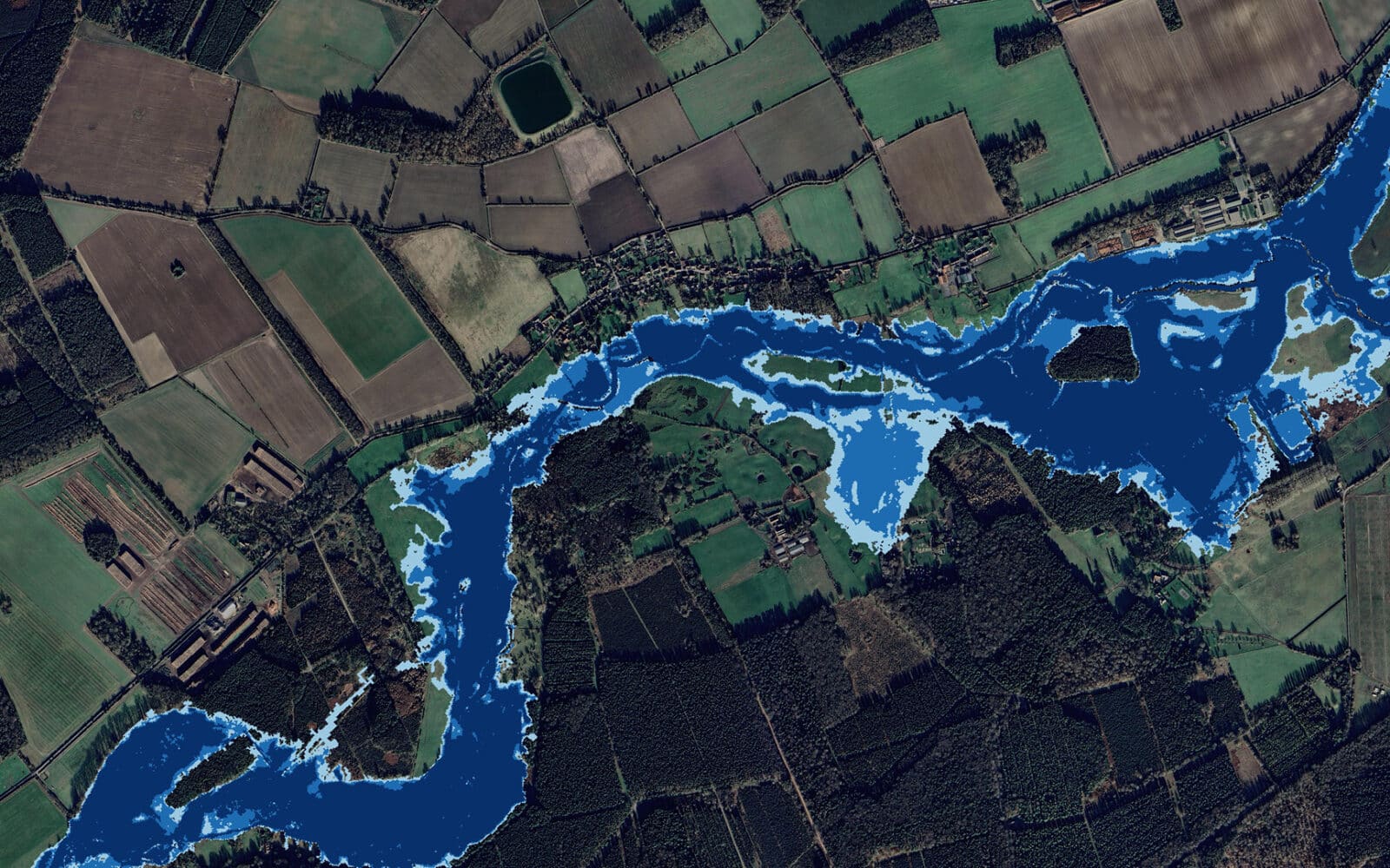 A satellite image shows a river winding through rural farmland and forested areas, with varying shades of blue indicating different water levels or potential flood zones.