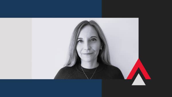 A woman with straight, shoulder-length hair and a slight smile faces the camera. The background features geometric shapes in blue, black, gray, and red.