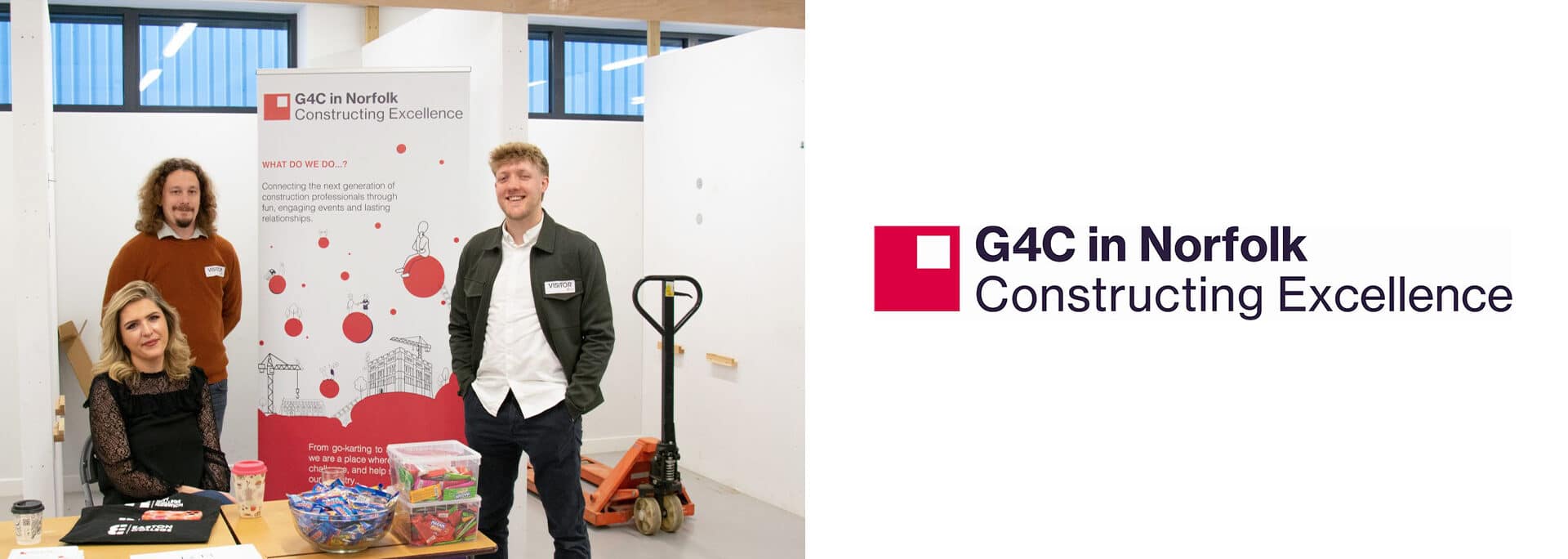 Three people stand and sit at a promotional table for G4C Norfolk at Constructing Excellence, featuring informational materials and a G4C banner in a modern indoor space.