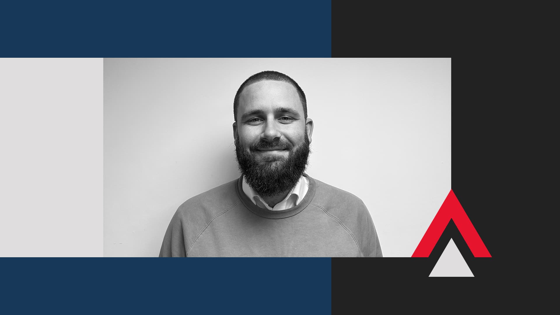 A man with a beard and short hair is smiling at the camera; the image background features geometric shapes in blue, black, white, and red.