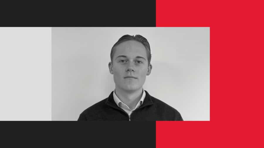 A young man with short, neatly styled hair and a collared shirt stands against a plain white background, framed by geometric blocks of black, white, and red.