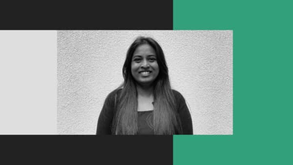 A woman with long hair stands in front of a textured wall, smiling at the camera. The image features Retb-inspired black, white, and green graphic borders.